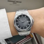 Stainless steel wristwatch with a black textured dial, silver hands and markers, and a date window at 3 o'clock on a metal bracelet.