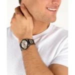 Man wearing a silver stainless steel wristwatch on his left wrist while smiling, wearing a white tee.