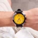 Close-up of a Maserati wristwatch with a bright yellow dial on a black strap, worn on a forearm.