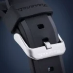 Close-up of a black rubber watch strap with a silver metal buckle.