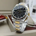 Two-tone stainless steel chronograph watch with gold accents, black textured dial and tachymeter bezel on display.