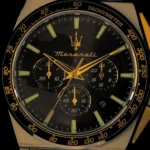Close-up of a Maserati chronograph watch dial with gold hands, green-lumed markers, and a tachymeter bezel.